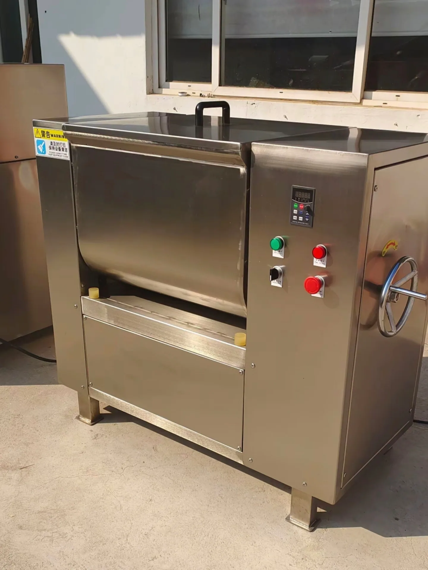Commercial stainless steel meat stuffing mixer with a safety lid for uniform food blending.