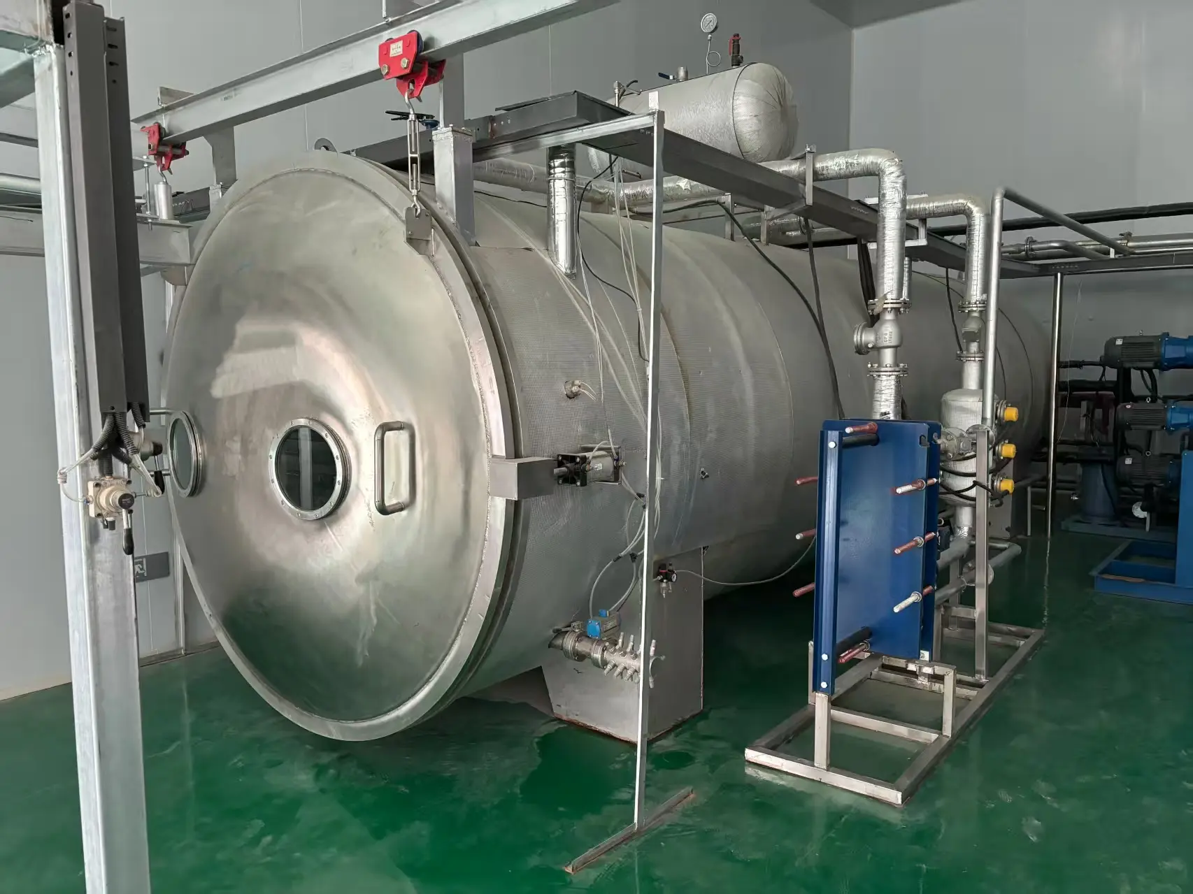 Massive stainless steel freeze drying chamber equipped with an overhead hoist system for easy tray loading.