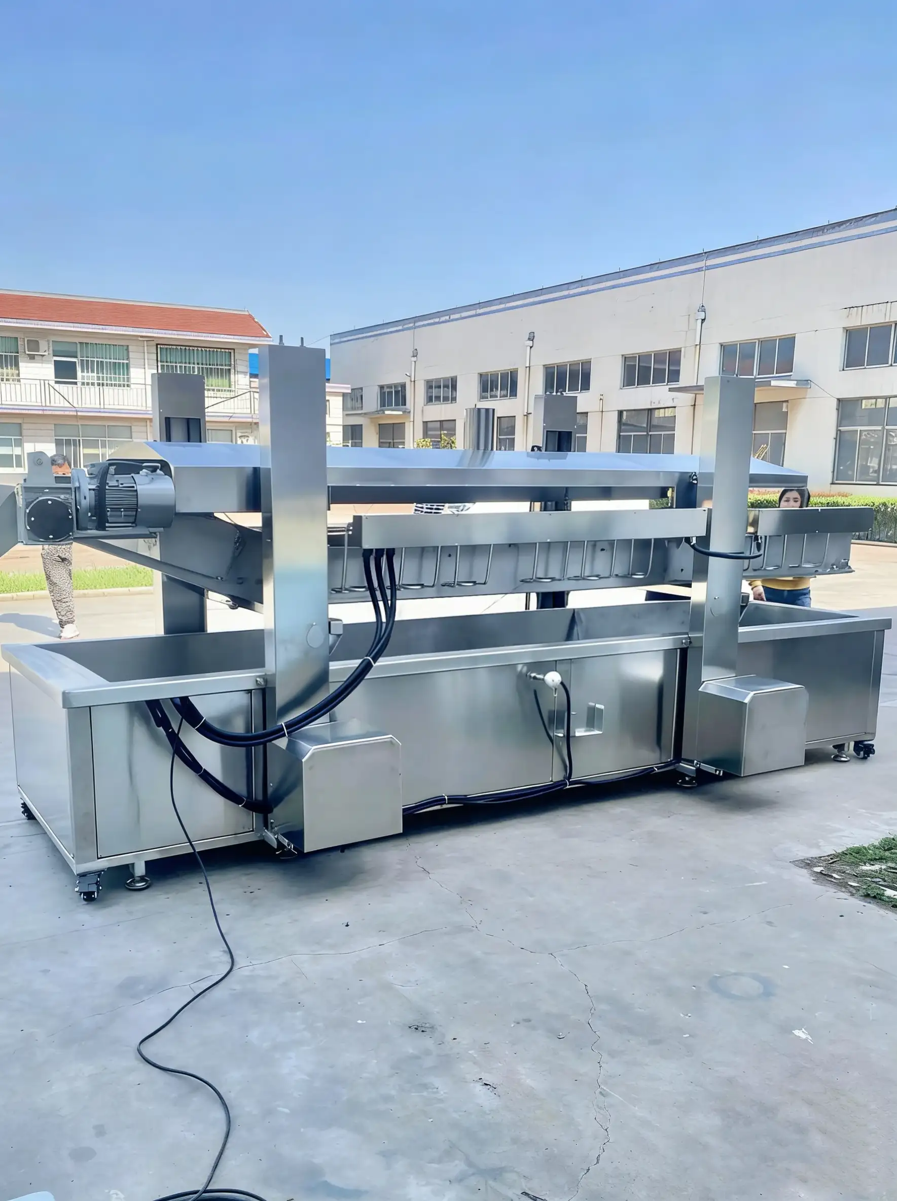 Industrial continuous deep frying machine line with automatic lifting hood for large-scale food processing.